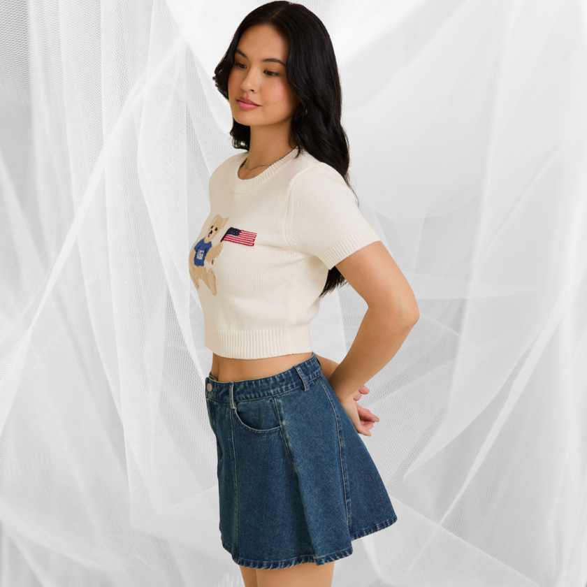 Woman wearing a white USA teddy bear crop top and denim mini skirt – perfect patriotic summer outfit